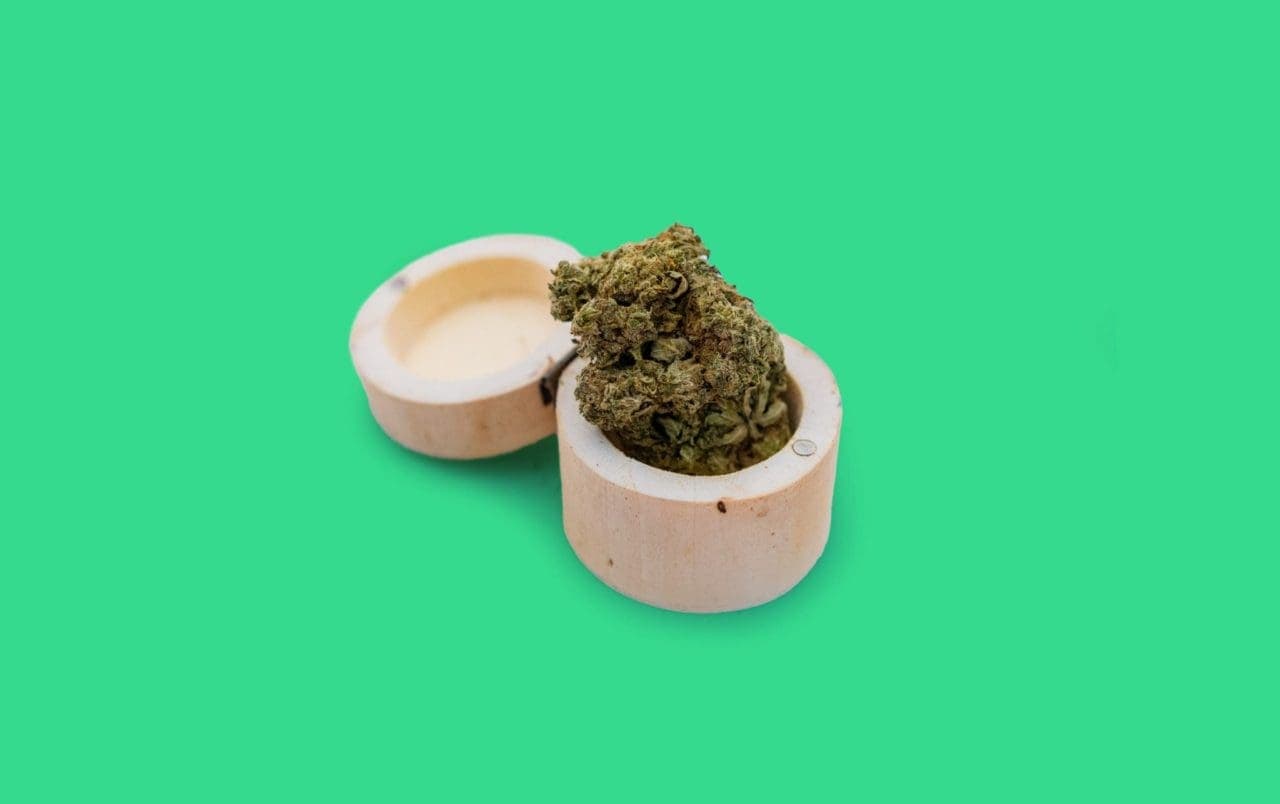 cannabis flower in an open wooden container with green background